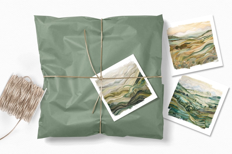 May include: A set of three landscape art prints featuring abstract watercolor paintings of rolling hills and valleys in shades of green, brown, and beige. The prints are packaged in a green paper bag tied with twine.