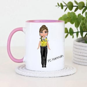 May include: White ceramic mug with a pink rim, featuring a cartoon illustration of a female police officer wearing a yellow vest and black trousers. The mug has the text "PC Hannah" printed on the side.