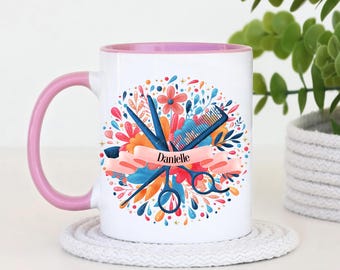 Peut inclure: Un mug en céramique blanche avec une anse et un intérieur rose clair. L'avant présente un motif coloré de ciseaux de coiffure bleus et d'un peigne sur des fleurs, avec une bannière en ruban rose portant le nom Danielle en noir.