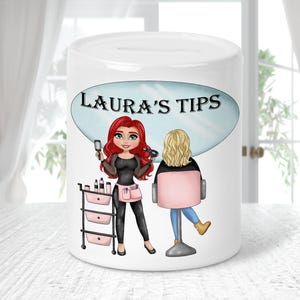 Puede incluir: Hucha de cerámica blanca con una ilustración de dibujos animados de una peluquera y una clienta. El texto "LAURA'S TIPS" está en un óvalo azul. La peluquera, con pelo rojo, sostiene herramientas cerca de un carrito con productos de belleza.