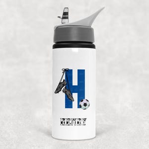 May include: A white water bottle with a grey lid and straw, featuring a large blue letter H, a pair of black football boots hanging from the letter, a football graphic, and the name HENRY printed in a black and white chequered font below.