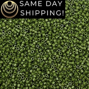 May include: A large collection of small, cylindrical olive green beads with a smooth, uniform finish. The image features a black rectangular overlay in the top left corner containing a gold circular logo and the text SAME DAY SHIPPING!