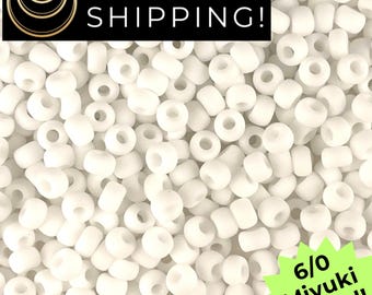 May include: A collection of opaque white round beads with a smooth finish. The image includes text that reads SAME DAY SHIPPING and 6/0 Miyuki Round. These small, uniform beads are arranged in a dense pile, showcasing their consistent shape and color.