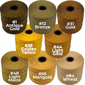 May include: Spools of colorful cord in various shades of gold, yellow, and beige. The image displays seven spools, each labeled with a number and color name, including "Antique Gold," "Bronze," and "Wheat." The cords are tightly wound, showcasing their texture.