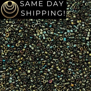 May include: Close-up of a pile of small, cylindrical beads in shades of dark green, black, and iridescent colors. The beads are densely packed together, creating a textured surface. The image includes the text "SAME DAY SHIPPING!"