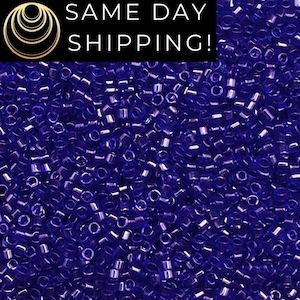 May include: Close-up of a pile of small, cylindrical, transparent, dark blue beads. The beads are scattered, creating a textured surface. The image includes the text "SAME DAY SHIPPING!" in a black rectangle.