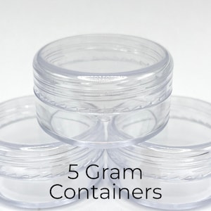 May include: Three clear, round, empty plastic jars stacked together. Each container features a screw-top lid and a smooth, transparent finish. The text 5 Gram Containers is printed in black on the front of the jars, indicating their capacity.