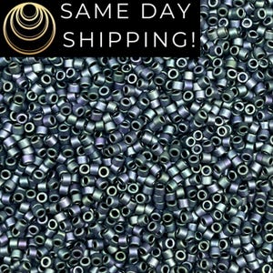 May include: A close-up image of a large quantity of small, round, dark blue and green iridescent glass beads. The beads have a metallic sheen and are perfect for jewelry making.