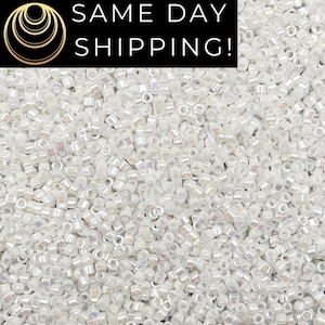 May include: A close-up shot of a large pile of small, white, iridescent beads. The beads are cylindrical with a slightly rectangular shape. The image has a black banner at the top with the words "SAME DAY SHIPPING!" in white.