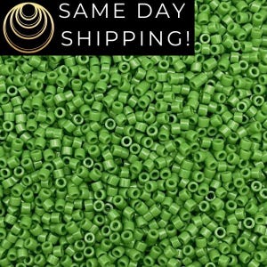 May include: A close-up image of a large quantity of small, round, green beads. The beads are all the same size and shape, and they are arranged in a random pattern.