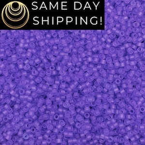 May include: A close-up view of a large quantity of small, round, translucent purple beads. The beads are all the same size and shape, and they are arranged in a random pattern.