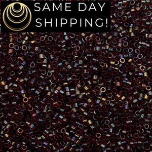 May include: A close-up shot of a large pile of small, cylindrical beads. The beads are primarily a deep burgundy color with iridescent highlights. The image includes the text "SAME DAY SHIPPING!" in white letters on a black background.