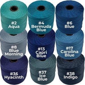 May include: Nine spools of colorful cord in various shades of blue, from aqua to indigo. Each spool is labeled with a number and color name, including "Aqua," "Bermuda Blue," and "Indigo." The spools are tightly wound and ready for crafting.