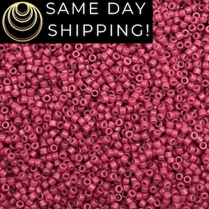 May include: A close-up image of a large quantity of small, round, red beads. The beads are all the same size and shape, and they are arranged in a random pattern.