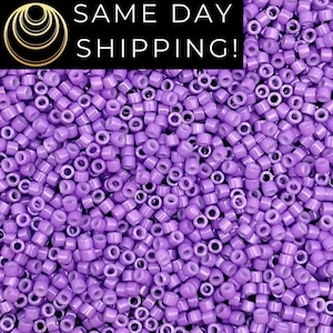 May include: A close-up shot of a pile of small, cylindrical lavender-colored beads. The beads are uniform in size and shape, with a hole running through the center of each. The image also contains the text "SAME DAY SHIPPING!" in a black rectangle.