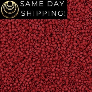 May include: A close-up image of a large quantity of small, round, red beads. The beads are all the same size and shape, and they are arranged in a random pattern.