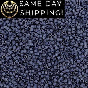 May include: A close-up image of a large quantity of small, dark blue, round seed beads. The beads are all the same size and shape, and they are arranged in a random pattern.
