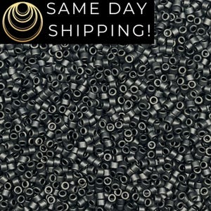 May include: A close-up image of a large quantity of small, round, black beads. The beads are all the same size and shape, and they are arranged in a random pattern.