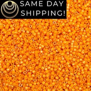 May include: A close-up image of a large quantity of small, round, orange beads. The beads are all the same size and shape, and they are arranged in a random pattern.