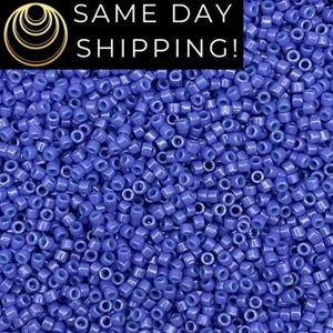May include: A close-up view of a large quantity of small, round, opaque, light blue seed beads. The beads are arranged in a random pattern, creating a textured surface.