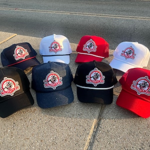 Peut inclure: Huit casquettes de camionneur noires, blanches, rouges et bleues avec un dos en maille blanche. Chaque casquette arbore un logo rouge et blanc avec le mot "Winchester" et un graphique représentant une lunette de visée et un cerf.
