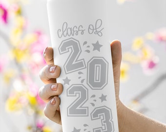 May include: White stainless steel tumbler with a gray design that says "class of 2023" with stars and water droplets.