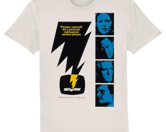May include: A white t-shirt with a black and yellow lightning bolt graphic and a blue and white television screen with the word "NETWORK" printed on it. The shirt also features four black and white portraits of people. The text "Prepare yourself for a perfectly outrageous motion picture" is printed on the shirt.