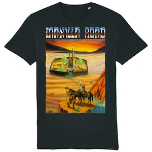 May include: Black t-shirt featuring a fantasy landscape graphic with the text "MANILLA ROAD" in a retro font. The graphic depicts a fortress, figures on horseback, and a river against a sunset backdrop. The shirt is made of a soft material.