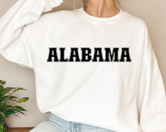Puede incluir: Sudadera blanca con texto negro que dice "ALABAMA" en una fuente negrita y universitaria.