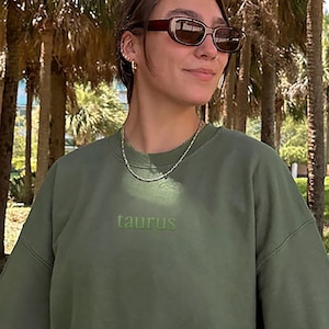 May include: A green sweatshirt with the word "taurus" embroidered in green on the front.