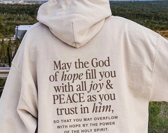 May include: A cream-colored hoodie with a brown text print that reads "May the God of hope fill you with all joy & PEACE as you trust in him, SO THAT YOU MAY OVERFLOW WITH HOPE BY THE POWER OF THE HOLY SPIRIT. ROMANS 15:13".