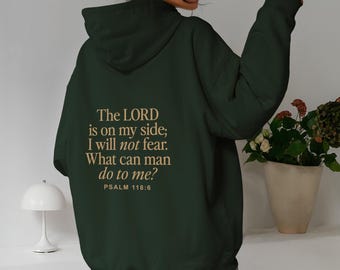 May include: Dark green hoodie with the text "The LORD is on my side; I will not fear. What can man do to me? PSALM 118:6" in a light brown color. The person is wearing leopard print pants.