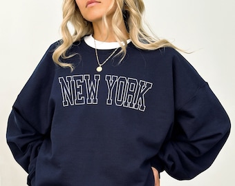 May include: A navy blue sweatshirt with the text "NEW YORK" in white outlined letters.