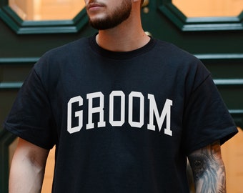 May include: A black t-shirt with the word "GROOM" printed in white on the front.