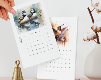 May include: Two watercolour paintings of birds on a calendar. The top painting shows two ducks in a pond. The bottom painting shows a hummingbird in flight. The calendar is for November.