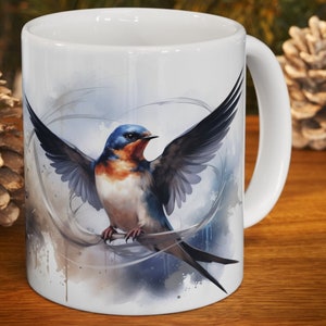 May include: White ceramic mug featuring a detailed illustration of a swallow with outstretched wings. The bird has blue, orange, and white plumage, set against a soft, watercolor-style background. The mug has a standard handle.