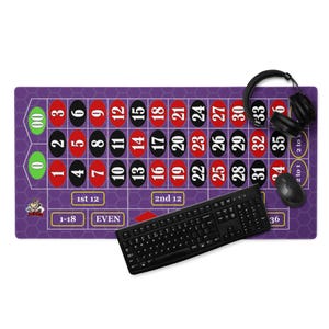 Pode incluir: Um tapete de rato para jogos roxo com um design de roleta, com números vermelhos e pretos. Um teclado, rato e auscultadores pretos também estão presentes. O tapete do rato tem os textos "1st 12", "2nd 12", "1-18" e "EVEN".