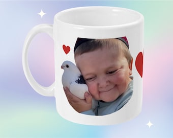 May include: White ceramic mug with a photo of a young child holding a white dove. The photo is surrounded by red hearts.