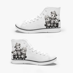May include: White high-top trainers with a panda family illustration. The black and white panda bears wear hats and scarves. The trainers have white laces and a grey trim around the sole. A fun and unique design for casual wear.