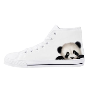 May include: White high-top canvas trainer with a panda bear graphic on the side. The panda has black ears, eyes, and paws, with a white face and body. The trainer has white laces and a black stripe along the sole.