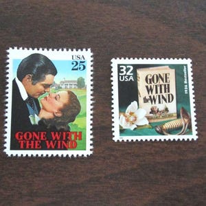 May include: Two vintage postage stamps. One features a couple kissing with the text "GONE WITH THE WIND" and "USA 25". The other stamp shows the book cover, a flower, and the text "GONE WITH THE WIND" and "USA 32".