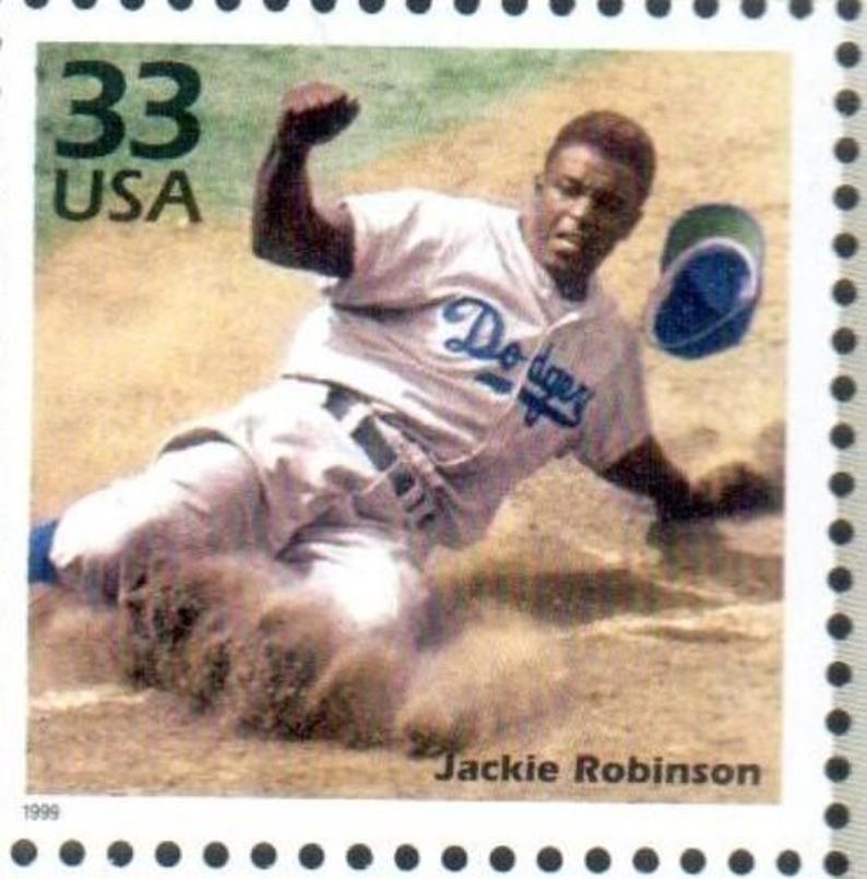 Puede incluir: Un sello postal estadounidense vintage de 33 centavos con una foto en blanco y negro de Jackie Robinson desliz&aacute;ndose hacia el home plate. El sello tiene el texto "33 USA" y "Jackie Robinson" impreso en &eacute;l.