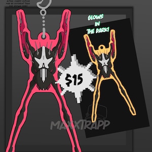 Puede incluir: Un dije rosa y negro con un diseño único, con un llavero en la parte superior. La imagen incluye el texto "GLOWS IN THE DARK!" y el precio "$15". El contorno del dije puede variar.
