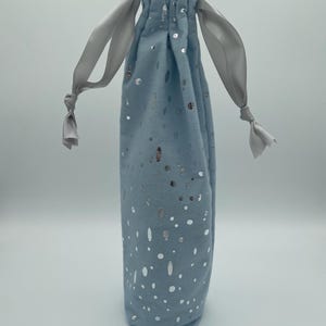 May include: A light blue drawstring bag with silver glitter confetti. The bag has white satin drawstrings.