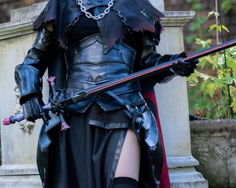 以下が含まれることがあります： 黒と赤のコスプレ衣装を着た人物が剣を持っています。コスチュームには、黒いボディス、スカート、ケープが含まれています。人物は庭の石段に立っており、背景には花と石のプランターがあります。