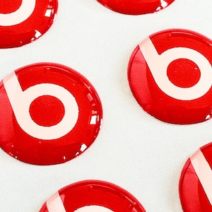 Op de afbeelding: Zes ronde rode stickers met een wit gestileerd "b"-logo. De stickers zijn glanzend en hebben een 3D-effect.