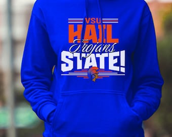 Può includere: Felpa con cappuccio blu reale con la scritta "VSU HAIL Trojans STATE!" in bianco e arancione. La felpa con cappuccio ha una tasca frontale e un cappuccio con coulisse. Il design include una grafica con elmo troiano.