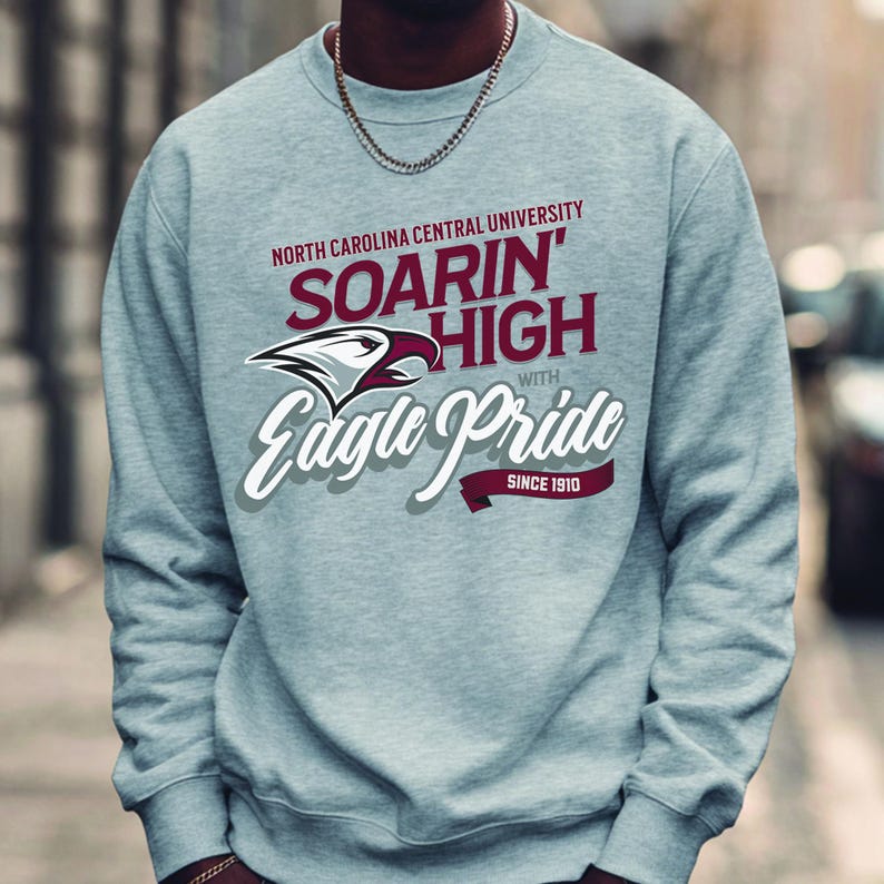 May include: A light gray sweatshirt with the text "North Carolina Central University" and "Soarin' High with Eagle Pride Since 1910". The sweatshirt features a maroon and white eagle logo.
