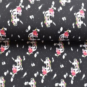 May include: Black fabric with a white anchor and pink flowers pattern. The anchor is surrounded by flowers and has a white outline. The background is black with white speckles.