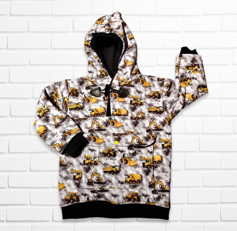 May include: A white hooded sweatshirt with a black zipper and a black drawstring. The sweatshirt has a pattern of yellow construction vehicles on a gray background.
